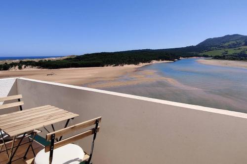 a wooden table and chairs on a balcony overlooking a beach at IAROS Pueblo del Sol in Mogro