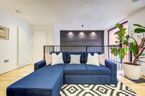 a blue couch in a living room with a plant at Shoreditch 3-Storey Maisonette - by Living Elite Apartments in Shoreditch