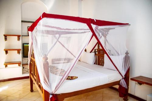 a bed with a canopy in a room at La Neisha Hotel Zanzibar in Stone Town