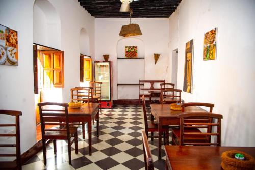 a restaurant with wooden tables and chairs and a checkered floor at La Neisha Hotel Zanzibar in Stone Town