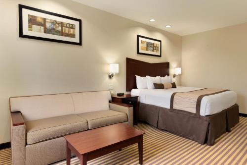 a hotel room with a bed and a couch at Baymont by Wyndham Victoria in Victoria