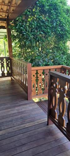 a wooden deck with a wooden fence and a tree at Pousada Vale da Cachoeira in Visconde De Maua