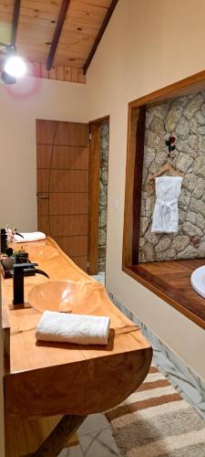 a bathroom with a sink and a stone wall at Pousada Vale da Cachoeira in Visconde De Maua
