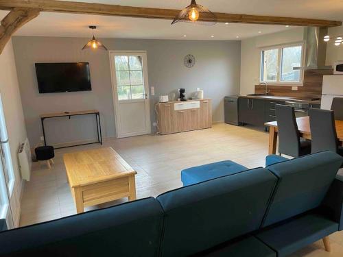 un salon avec un canapé bleu et une cuisine dans l'établissement Maison à la campagne à 10 minutes d’Honfleur, à Beuzeville