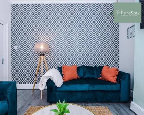 a living room with a blue couch in front of a wall at Fantastic Four Bedroom Family Home By PureStay Short Lets & Serviced Accommodation Merseyside Liverpool in Liverpool