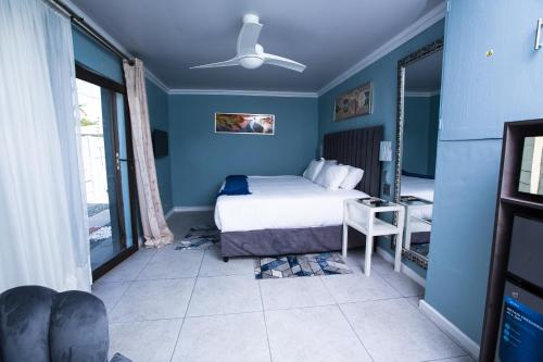um quarto com uma cama e uma parede azul em Hope and Faith at 14 on beach em East London