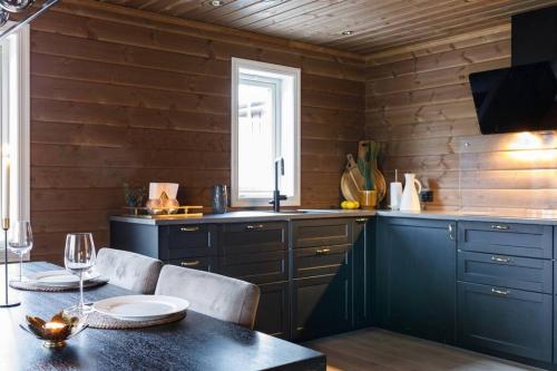 a kitchen with blue cabinets and a table and a window at Toppmoderne hytte i Beito in Beitostøl