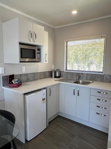 a kitchen with white cabinets and a sink and a microwave at Quality Inn Acapulco Taupo in Taupo