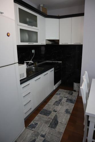 a kitchen with white cabinets and a sink at Prima Apartments in Pogradec