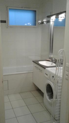 uma casa de banho com uma máquina de lavar roupa e um lavatório em Flat near Paris em Gennevilliers