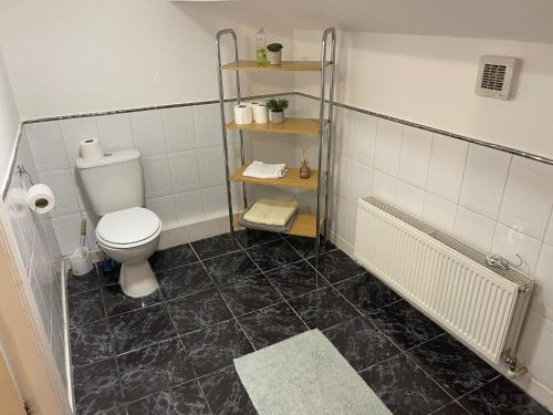 a bathroom with a toilet and a black tile floor at Great Apartman Liverpool in Liverpool
