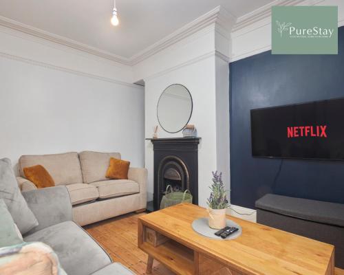 ein Wohnzimmer mit einem Sofa und einem TV in der Unterkunft Stunning Four Bedroom House By PureStay Short Lets & Serviced Accommodation Bradford With Parking in Bradford