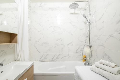 La salle de bains blanche est pourvue d'une douche et d'une baignoire blanche. dans l'établissement Appartement Glaciere, à Paris