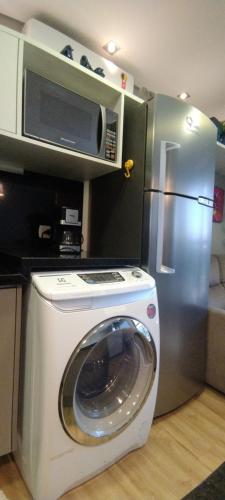 een keuken met een wasmachine en een koelkast bij Excelente Studio Completo Centro Curitiba - Ar Condicionado - 7th Avenue in Curitiba