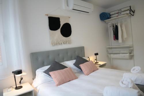 a bedroom with a white bed with pink and black pillows at Modern Apartament al costat del Parc de la Devesa in Girona