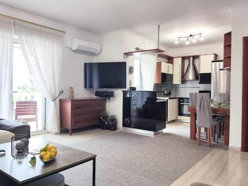 ein Wohnzimmer mit einem Tisch und einer Küche in der Unterkunft Varkiza Sea View Apartment - Free Parking in Vari