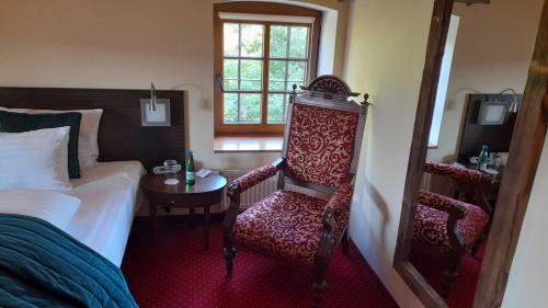 a bedroom with a bed and a chair and a window at Hotel Spichrz in Borcz