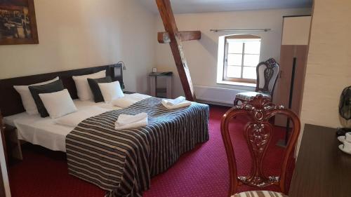ein Schlafzimmer mit einem Bett, einem Stuhl und einem Fenster in der Unterkunft Hotel Spichrz in Borcz