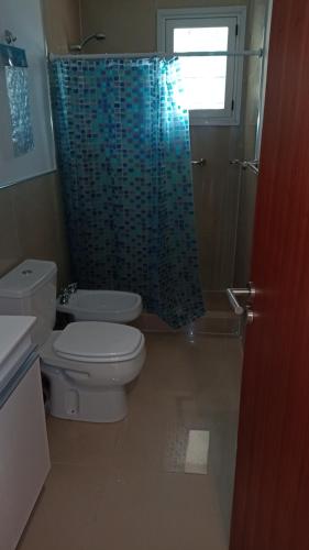 a bathroom with a toilet and a blue shower curtain at Aspromonte Departamentos in La Plata