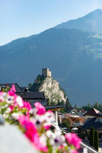 a castle on top of a mountain with pink flowers at Apart-Pension Bergland in Ladis