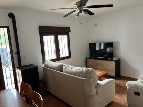 uma sala de estar com um sofá e uma ventoinha de tecto em Casa rural Labrador a 9k de Monfragüe em Torrejón el Rubio
