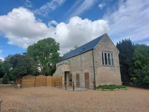 a large brick building with a fence in a yard at Luxury Victorian Hayloft barn self contained in South Witham