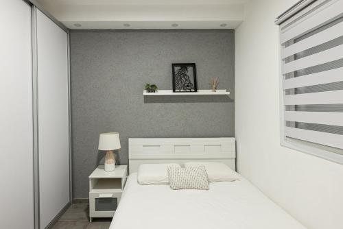 ein Schlafzimmer mit einem weißen Bett und einem Regal in der Unterkunft Oazis 1BR Apt,Central Old Town, Great location in Be’er Scheva