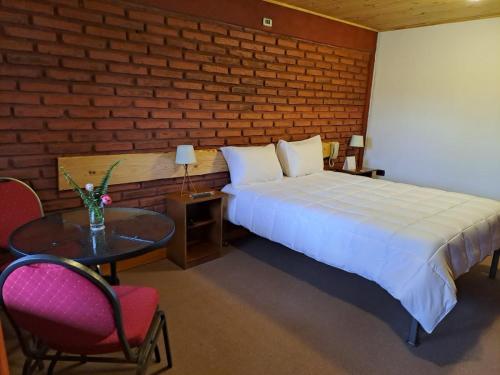 1 dormitorio con 1 cama, mesa y sillas en Hotel Artesanos, en Villa Alegre