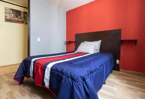 1 dormitorio con 1 cama con pared roja en Departamento ubicado en el centro histórico CDMX, en Ciudad de México