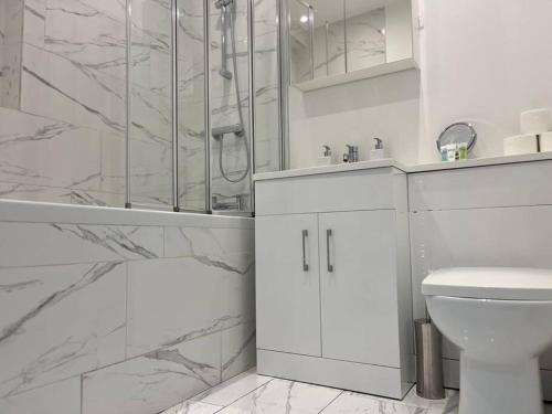 uma casa de banho branca com um chuveiro e um WC. em Modern & Spacious 2 bed Apartment at Addison Court - Sleeps 6, Free WIFI em Watford