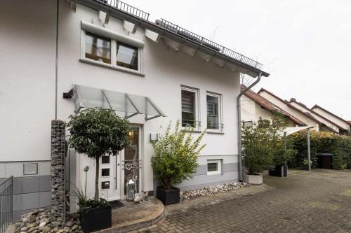 une maison blanche avec des plantes en pot devant elle dans l'établissement Apartments Harbour Apartments Höri 50m vom See am Yachthafen Moos bei Radolfzell, à Moos