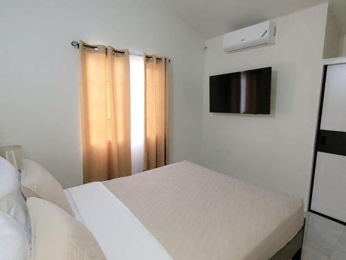 a white bedroom with a bed and a television at Sanel’s Luxury Stay in Discovery Bay