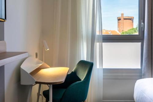 a room with a green chair and a window at Holiday Inn Perpignan by IHG in Perpignan