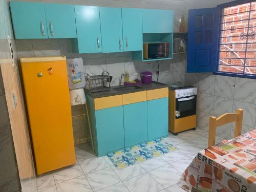 a kitchen with blue and yellow cabinets and a stove at Porto Colore praça Sete in Porto De Galinhas