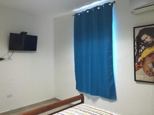 a bedroom with a blue curtain and a television at Panama Hat Hostel in Panama City