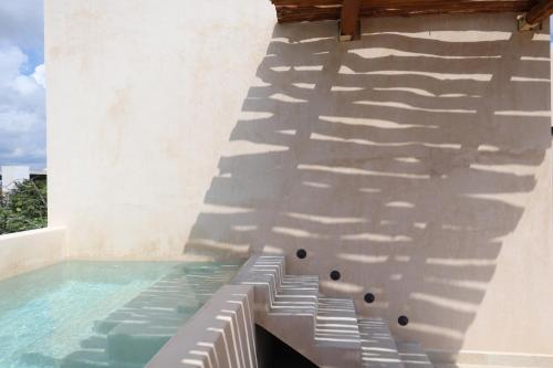 a swimming pool with a shadow on the side of a building at Akbal Tulum in Tulum