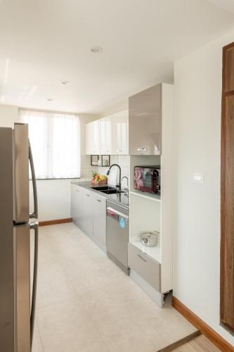 a kitchen with white cabinets and a stainless steel refrigerator at Mila Hotel in Kathmandu