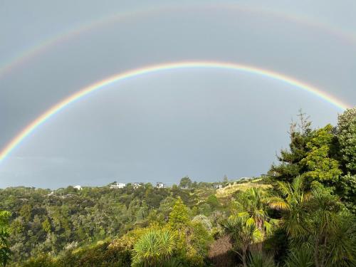 a rainbow in the sky over a forest at Tutukaka Sunrise in Tutukaka