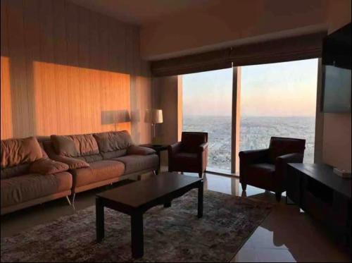 uma sala de estar com um sofá e duas cadeiras em Cozy Suite with Sky view em Riyadh