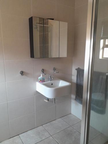 a white bathroom with a sink and a shower at Secunda BackPackers in Secunda