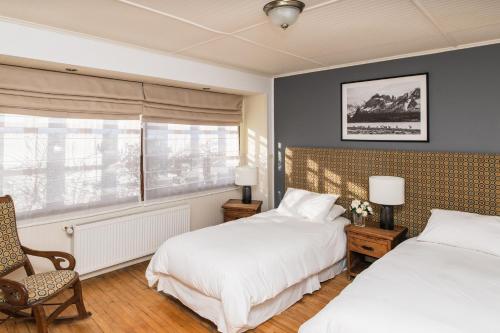 1 dormitorio con 2 camas, silla y ventana en Bories - Boutique Guest House, en Puerto Natales