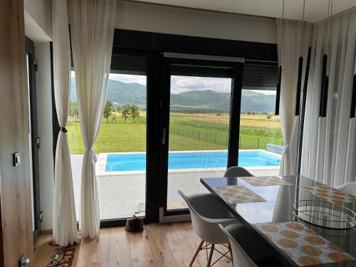 a dining room with a table and a view of a pool at Villa Biser Gacke in Sinac