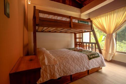 a bedroom with a bunk bed and a window at El Guayabal de Mindo in Mindo