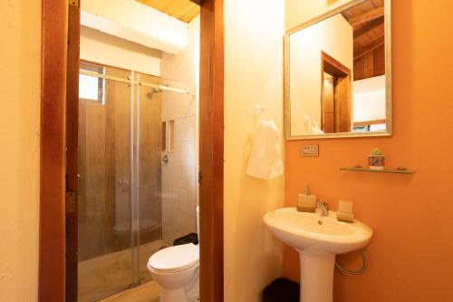 La salle de bains est pourvue de toilettes, d'un lavabo et d'une douche. dans l'établissement El Guayabal de Mindo, à Mindo