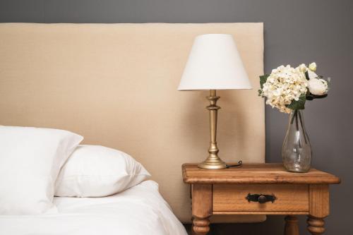 a lamp on a table with a vase of flowers at Bories - Boutique Guest House in Puerto Natales
