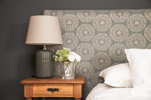 a lamp on a night stand next to a bed at Bories - Boutique Guest House in Puerto Natales