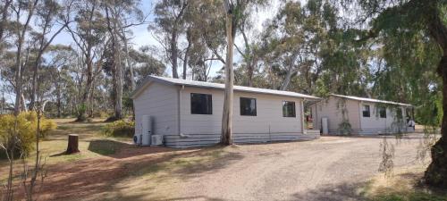 a small white house in the middle of a forest at Wedderburn Caravan Park in Wedderburn