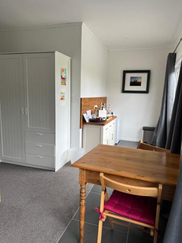 a dining room with a wooden table and a kitchen at Tutukaka Sunrise in Tutukaka