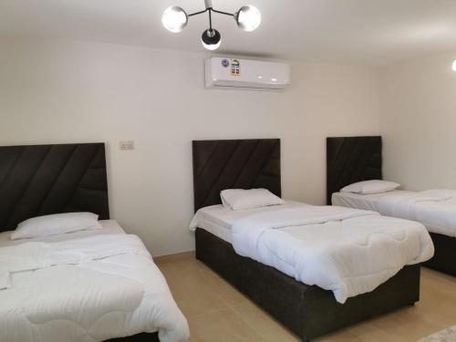 um quarto com 2 camas com lençóis brancos e um tecto em فيلا مسقط - Muscat Villa em Bawshar