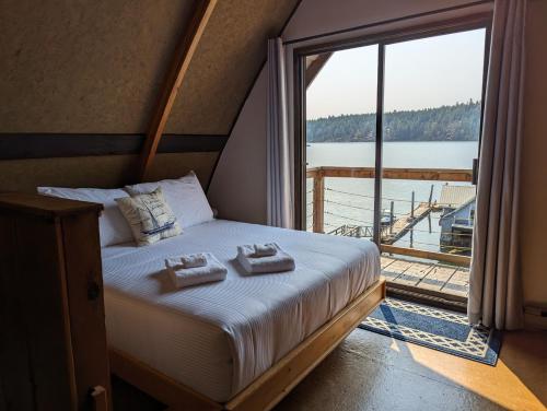 Jade Resort-Oceanfront Suites in Gowlland Harbour في Heriot Bay: غرفة نوم عليها سرير وفوط ونافذة كبيرة